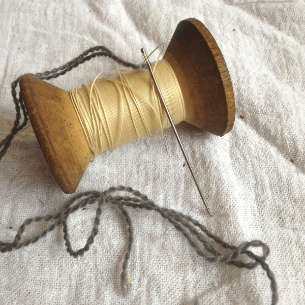 a darning needle in a mending basket