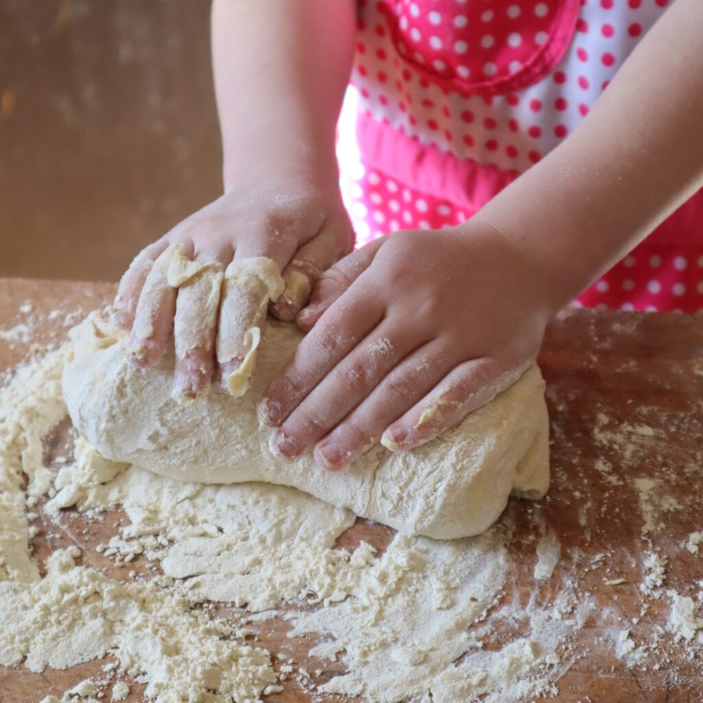 child's hands kneading bread dough
