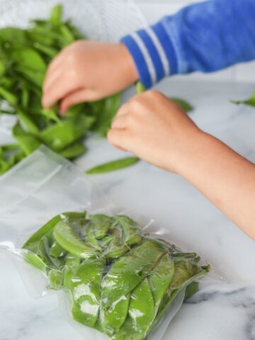 children putting snap peas into freezer bags