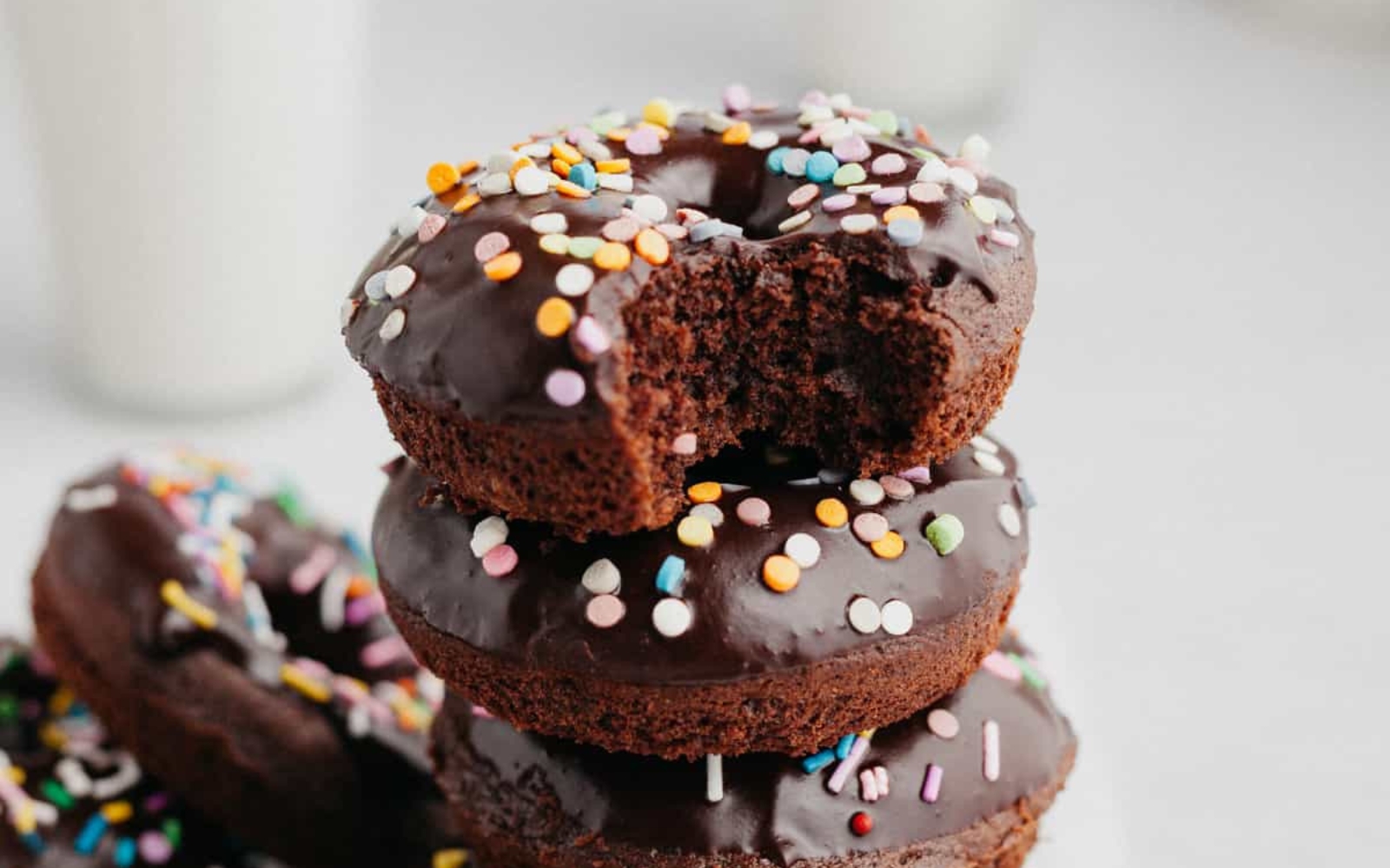 stack of chocolate frosted donuts with colorful sprinkles
