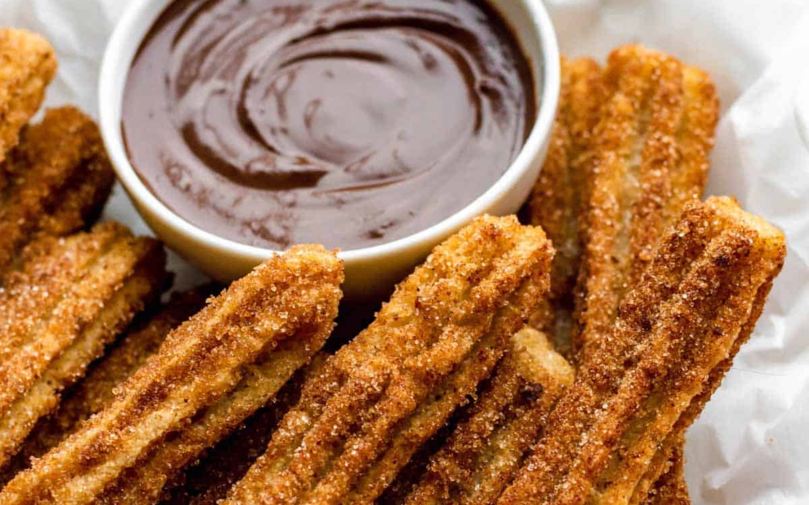 a plate of churros with chocolate sauce in a bowl