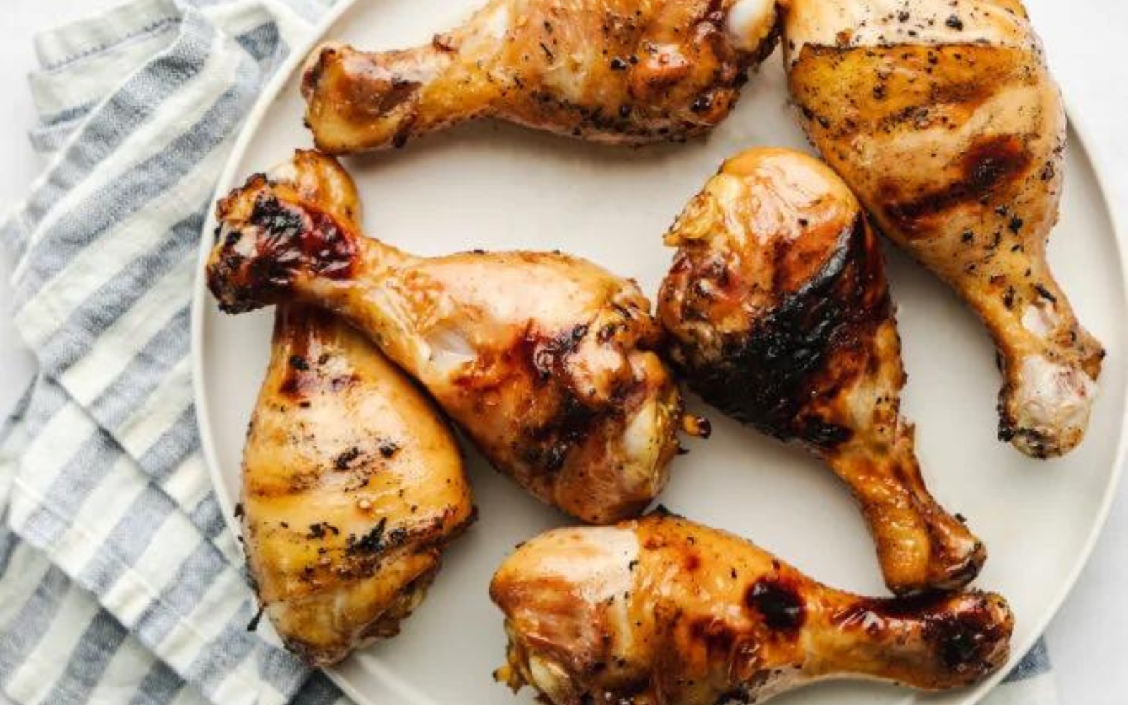 white plate full of grilled chicken drumsticks