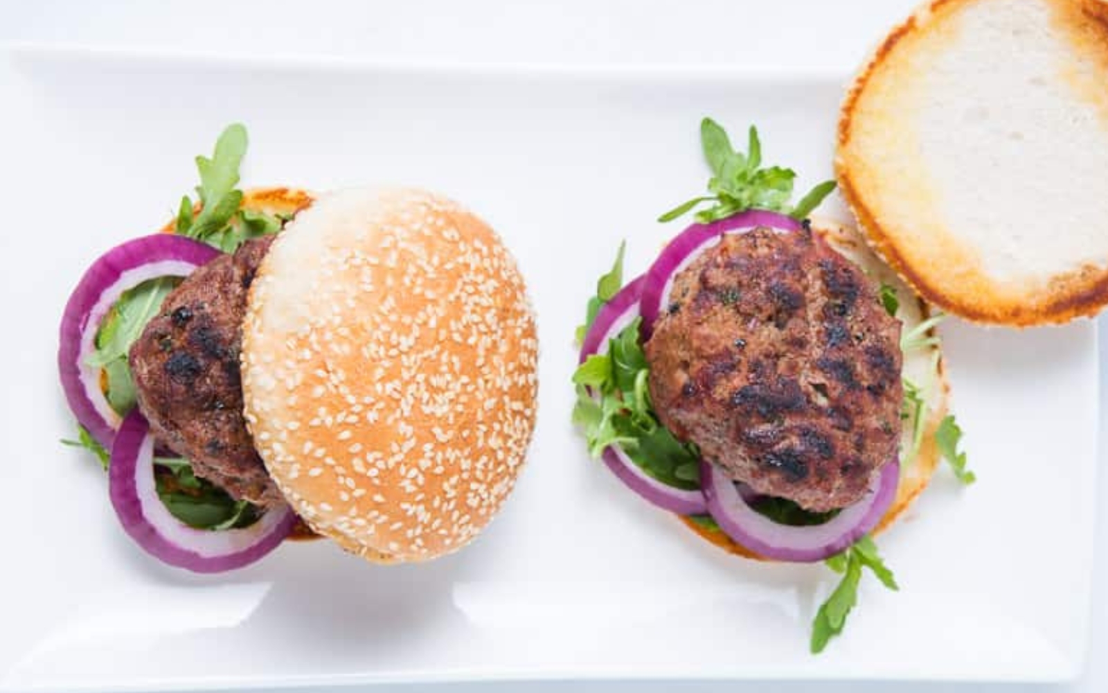 two lamb burgers on a white plate