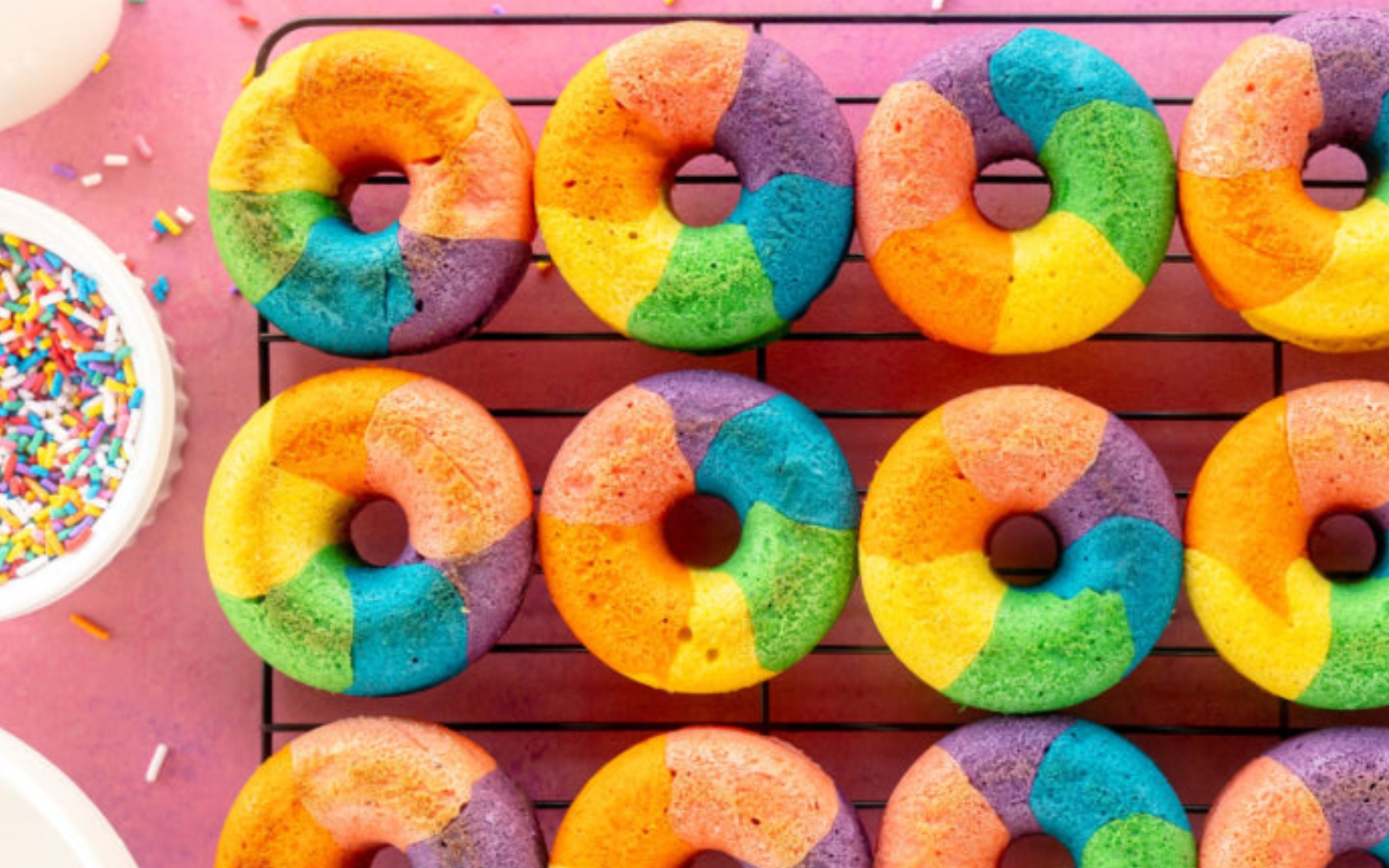 cooling rack filled with rainbow colored donuts