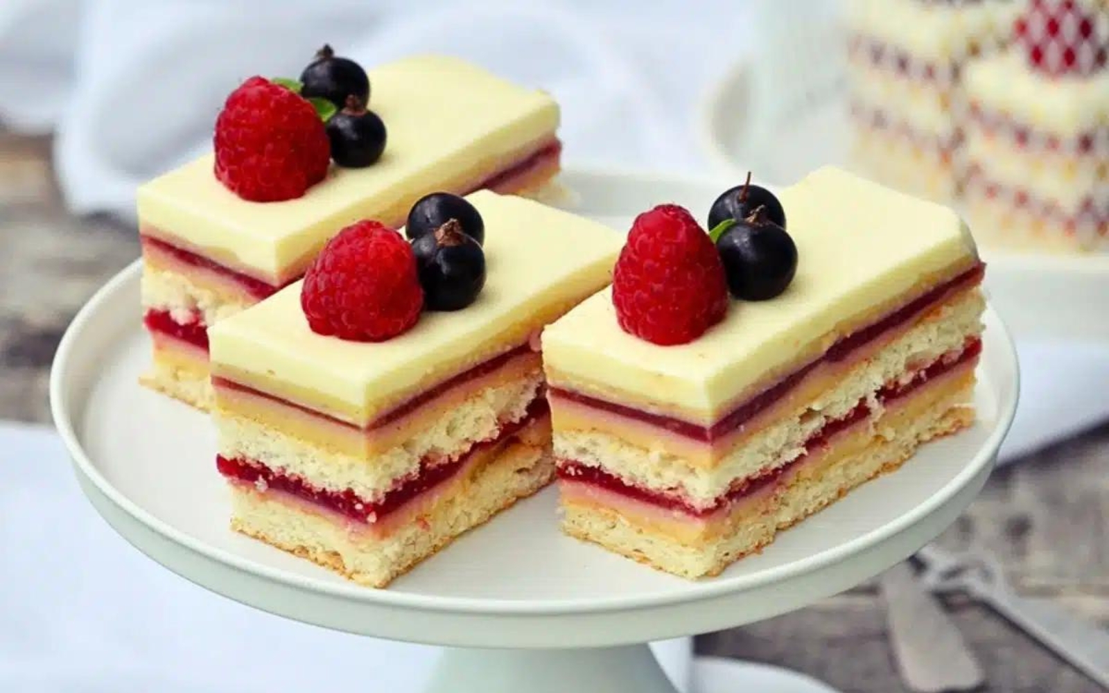 a cake stand with three slices of berry Bavarian cake
