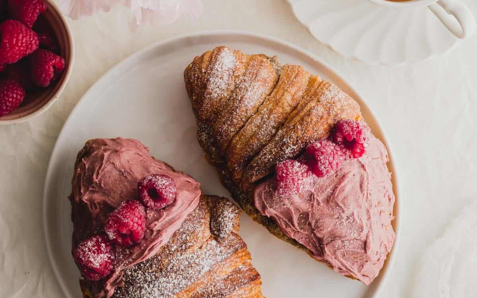 two frosted raspberry croissants on a plate