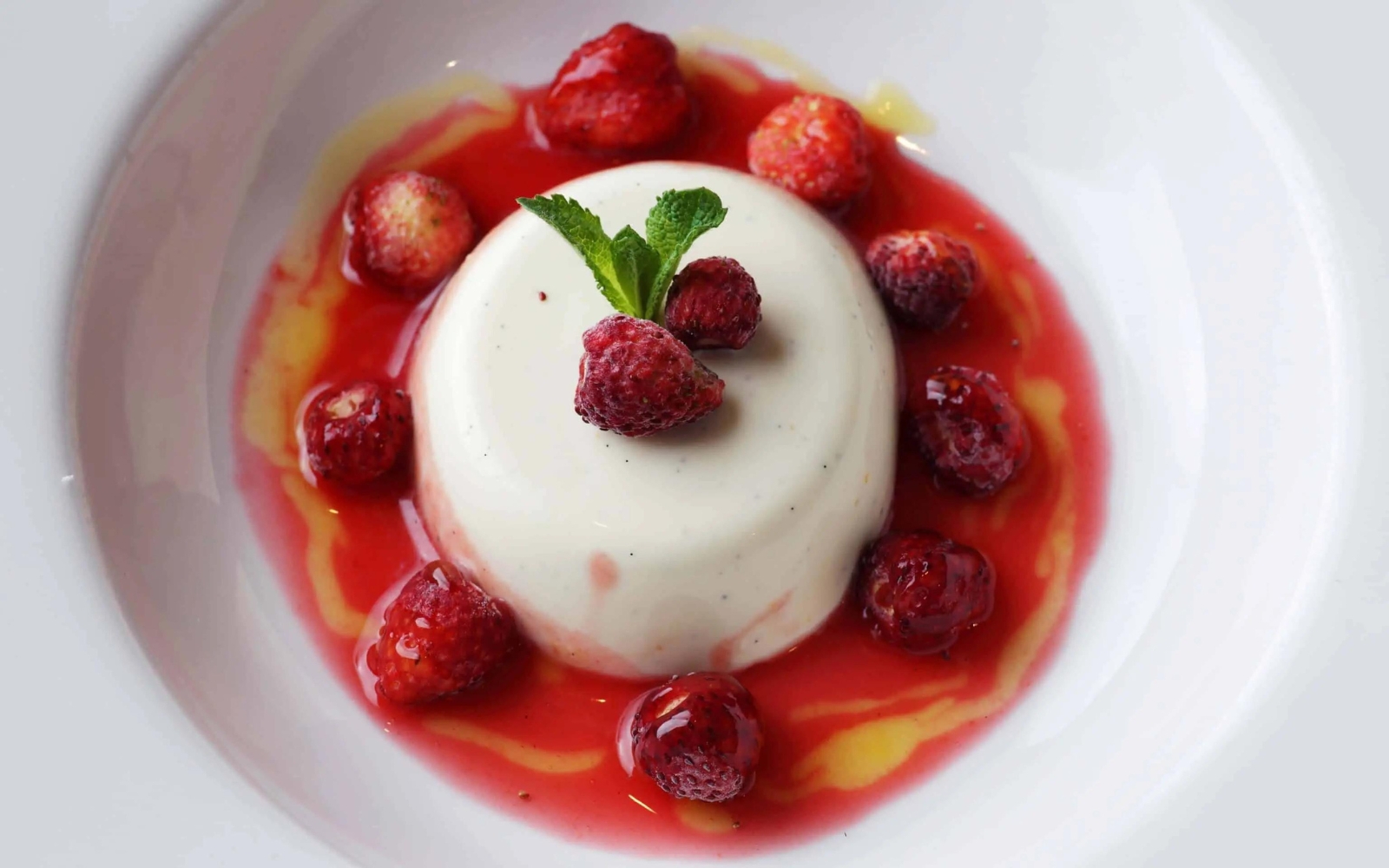 a panna cotta with raspberry sauce and raspberries