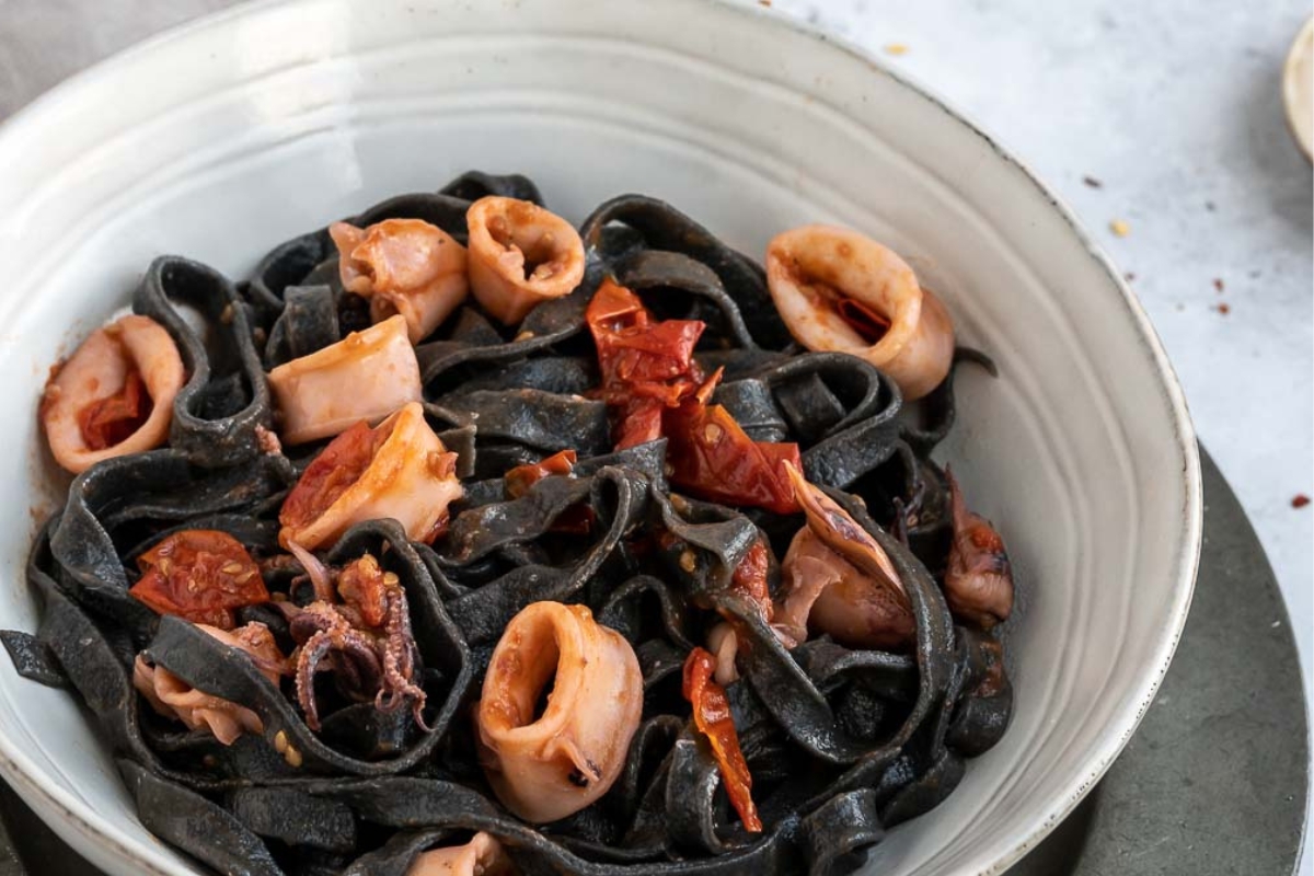 white bowl filled with black squid ink pasta