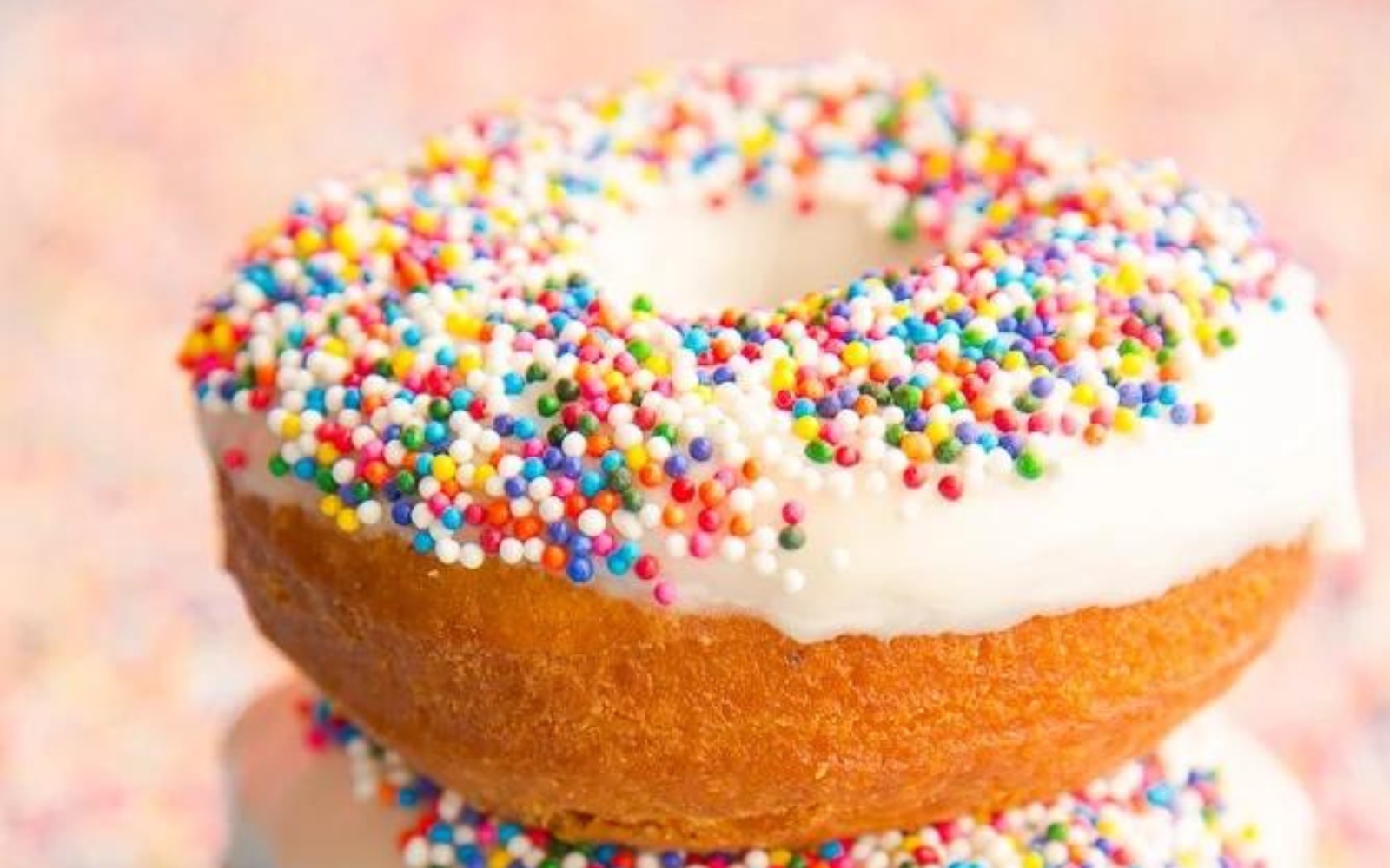a tres leches donut covered with frosting and rainbow sprinkles.
