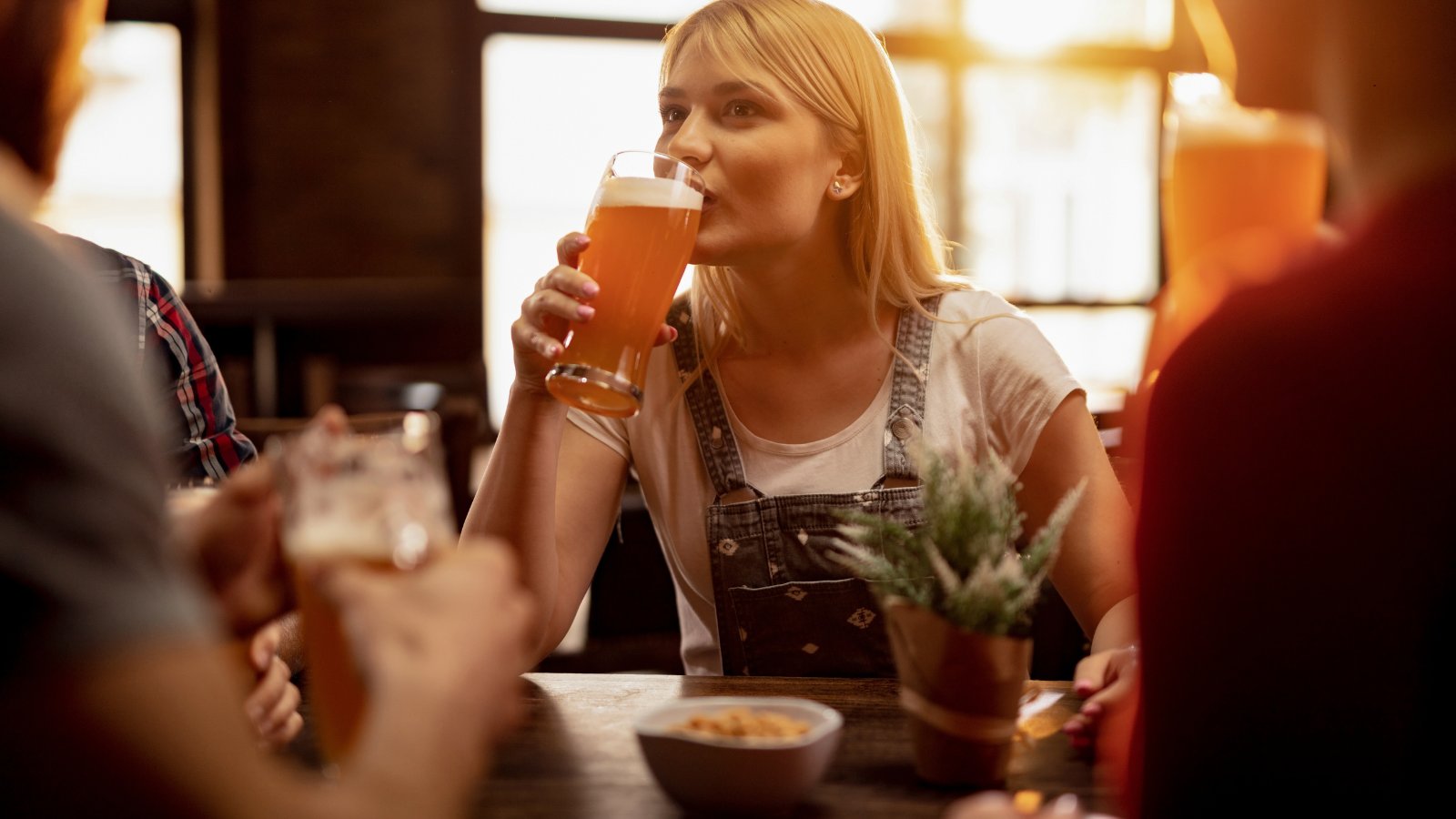 Woman drinking pint of beer with friends.