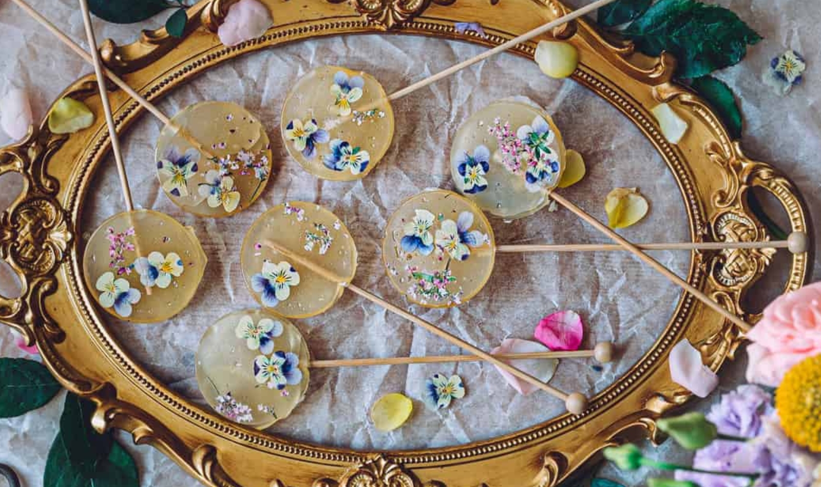 a gilt tray filled with fancy pressed flower lollipops