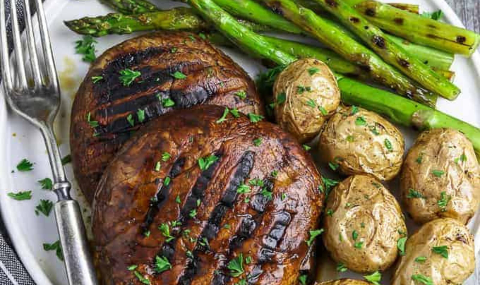 a plate of grilled portobello steaks, potatoes, and asparagus