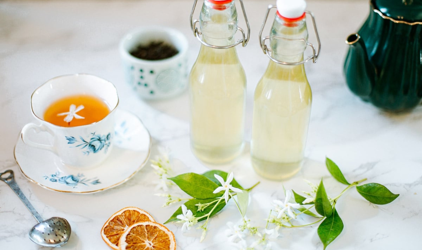 little bottles of jasmine simple syrup and a teacup of jasmine tea