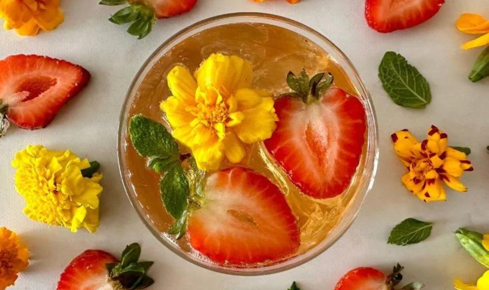 a kombucha cocktail with strawberries and marigolds