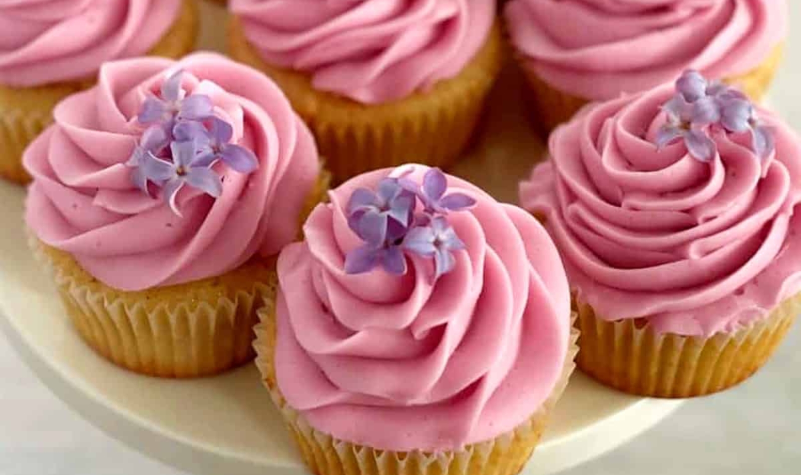 lilac cupcakes with pink frosting topped with lilacs