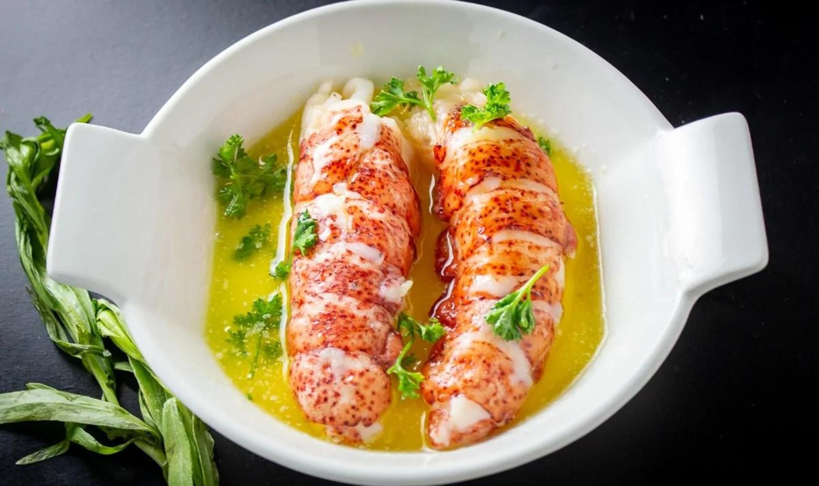 two lobster tails on a plate with broth