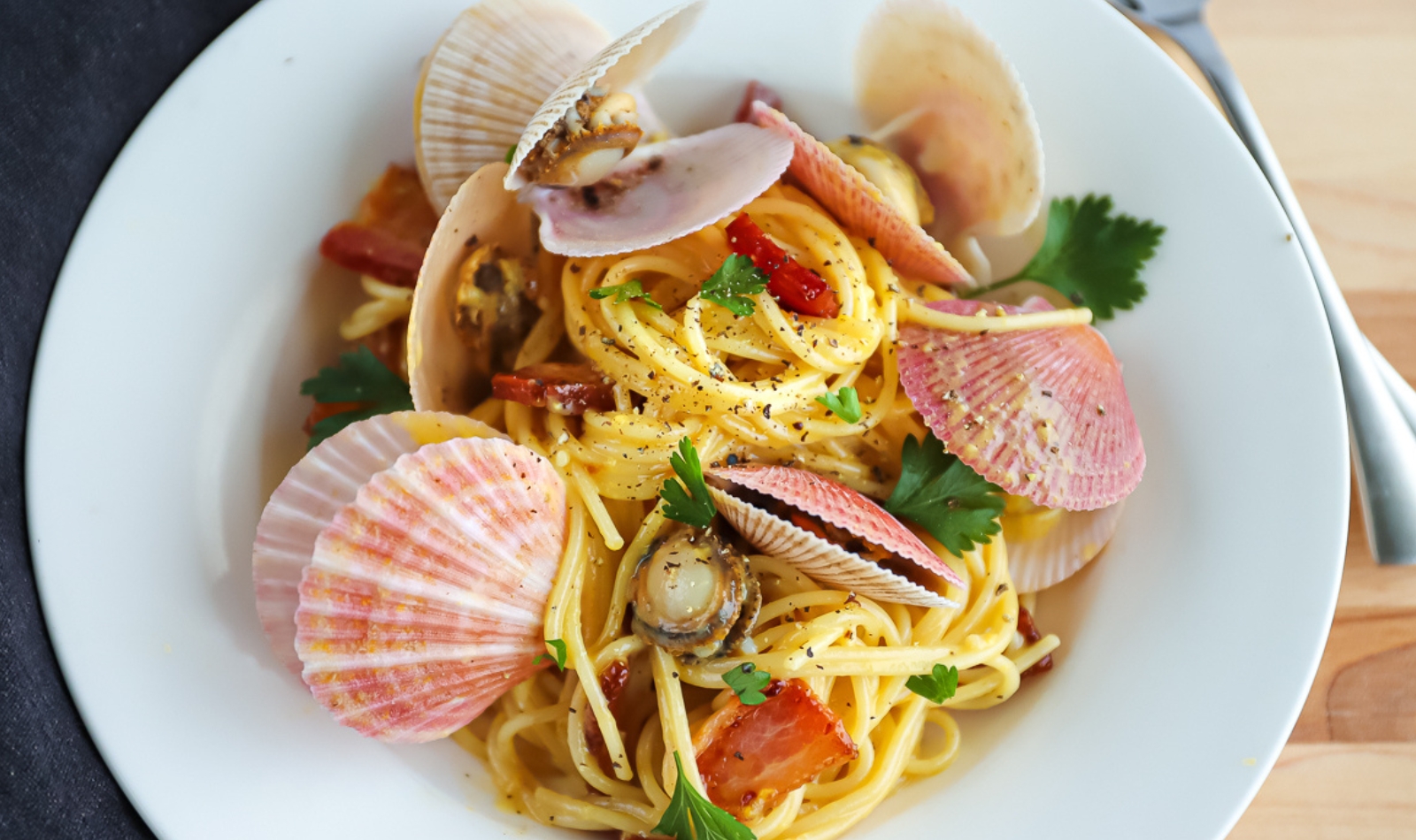 a plate of bacon and scallop pasta