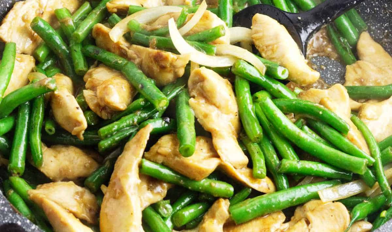Chicken tenders and green beans sauteed in a black cast iron pan