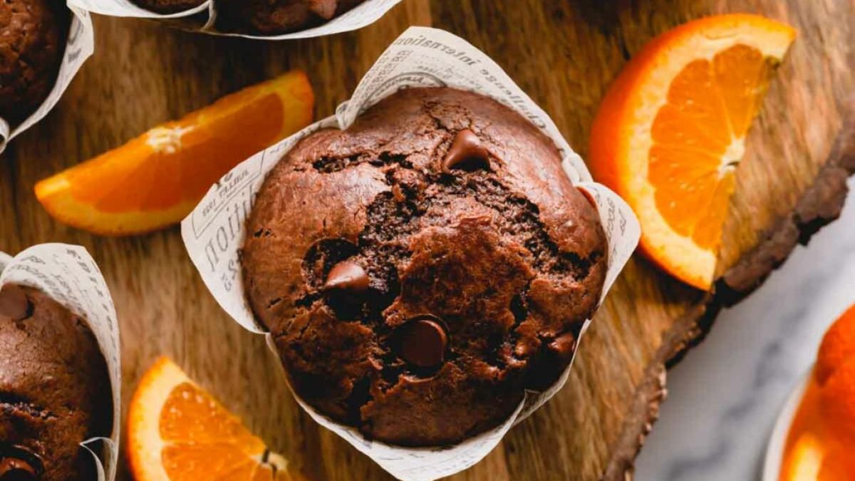 Orange and chocolate muffins served on wooden board