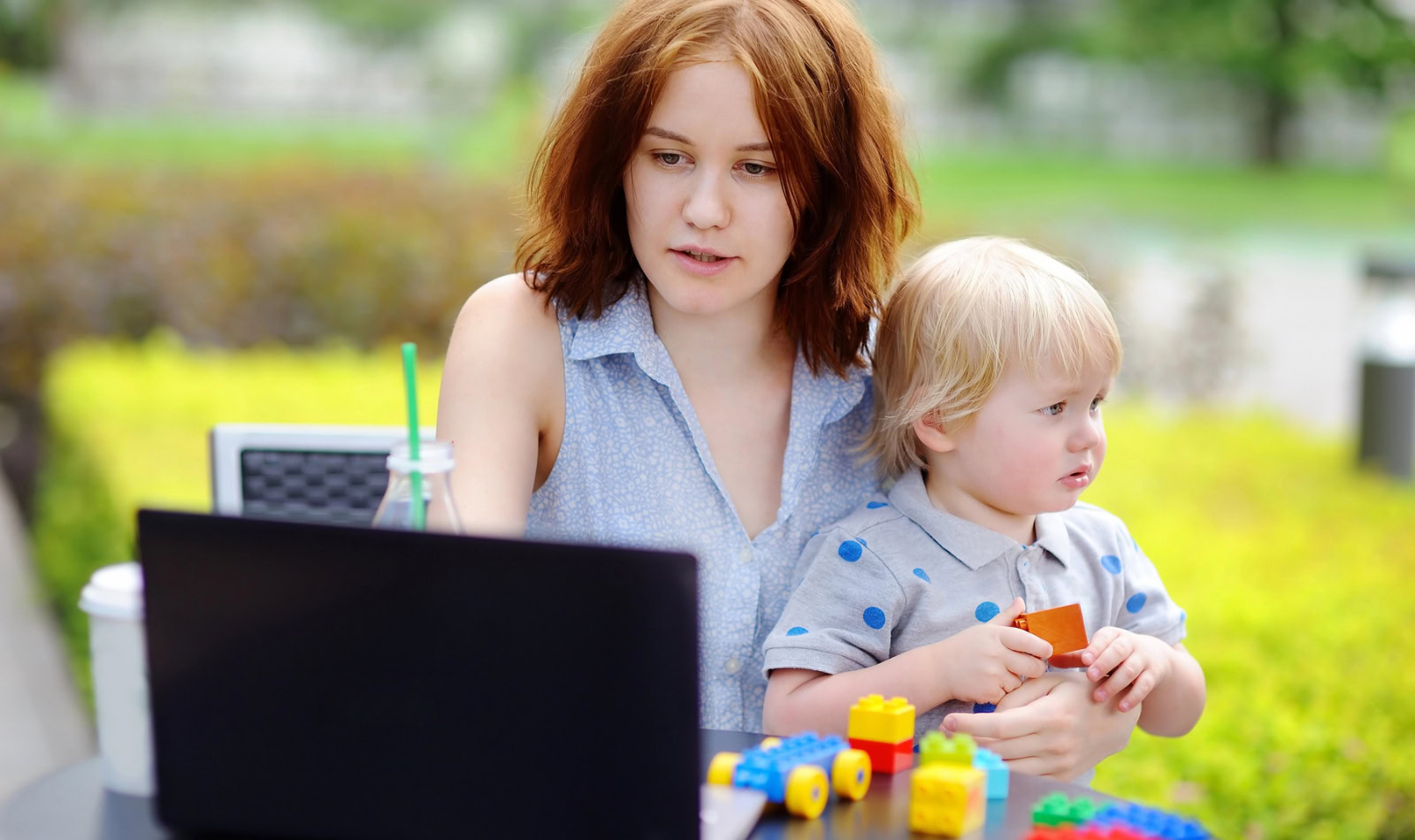 woman with laptop and young child in the park