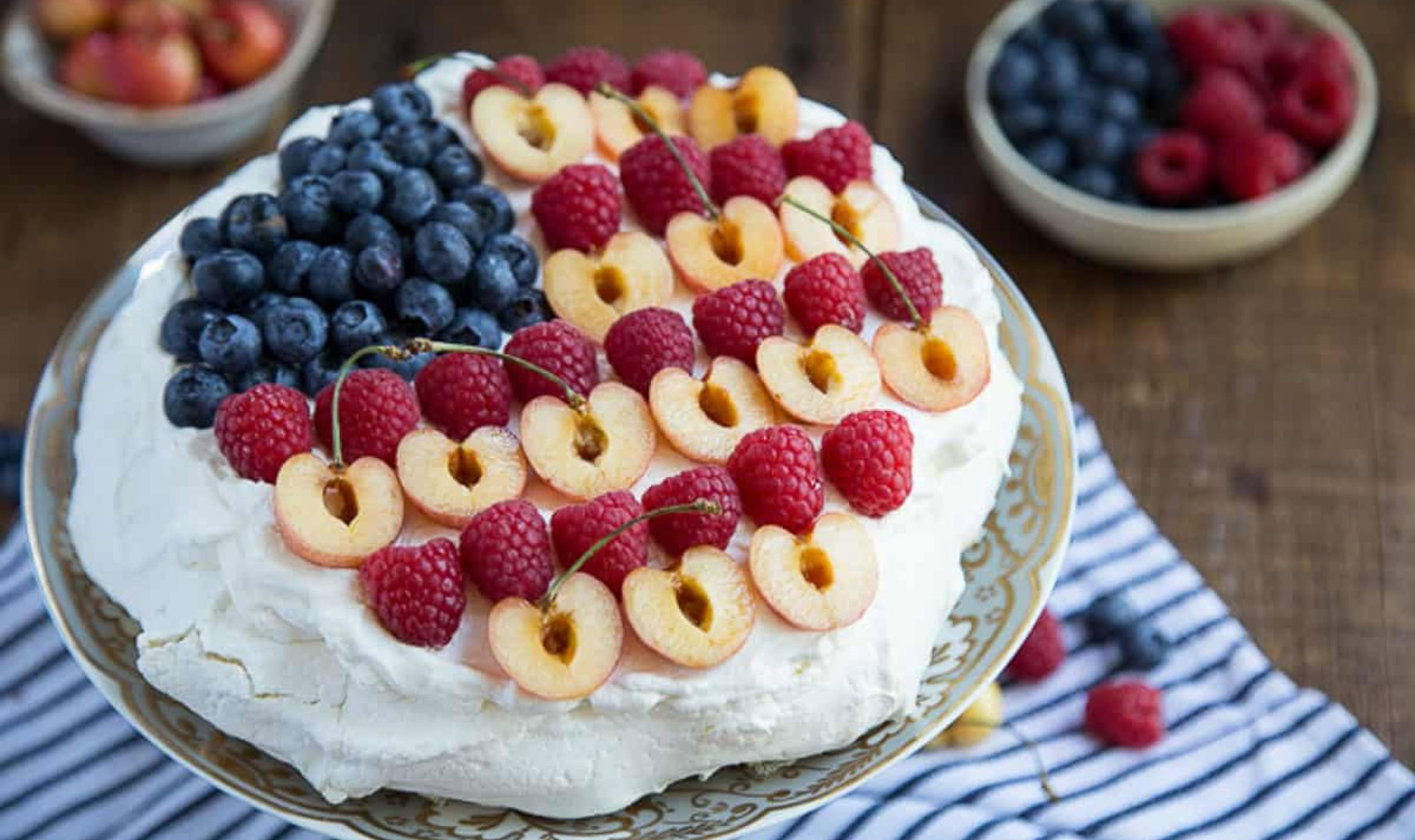 a pavlova with blueberries, raspberries, and cherries