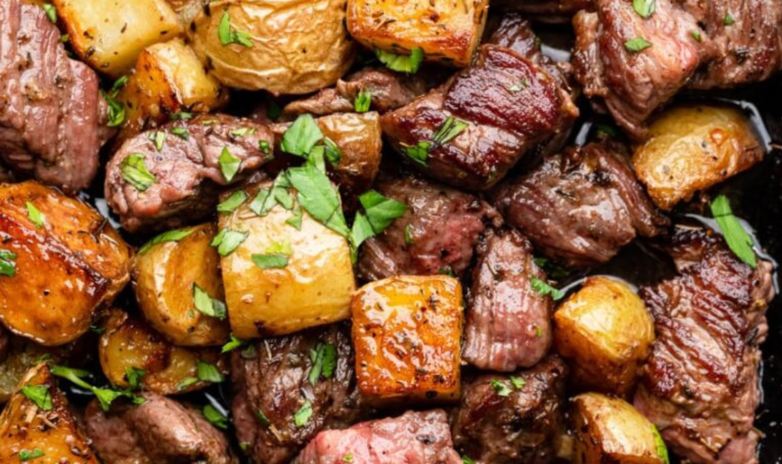 juicy bits of steak bites, garlic butter and potatoes with some green herbs