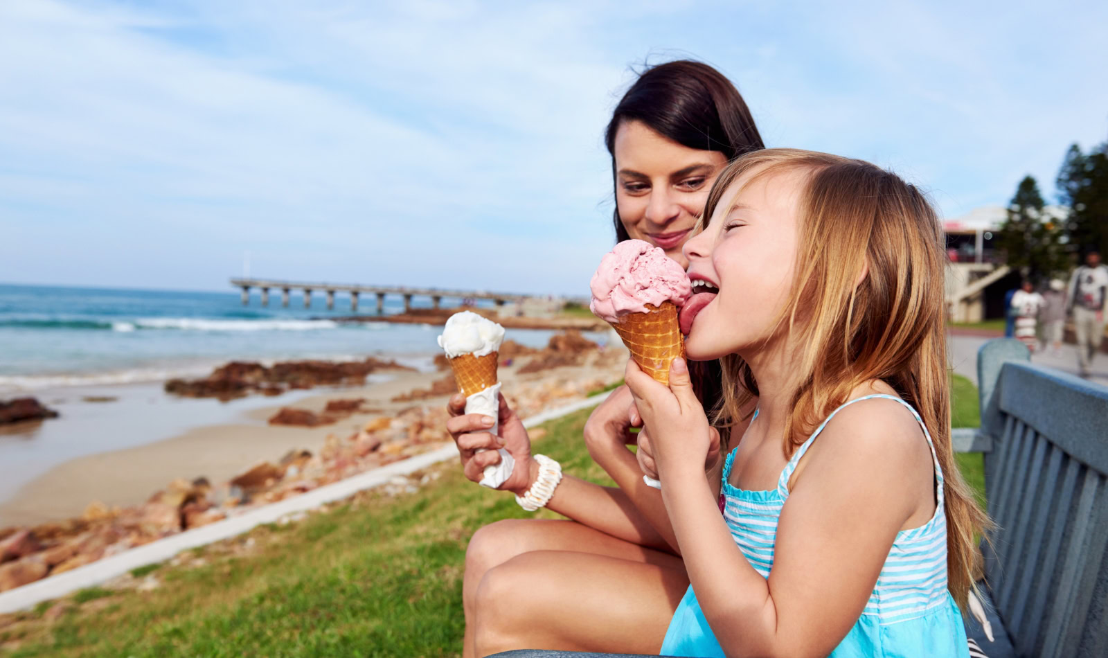 mom and daughter getting ice cream by the sea