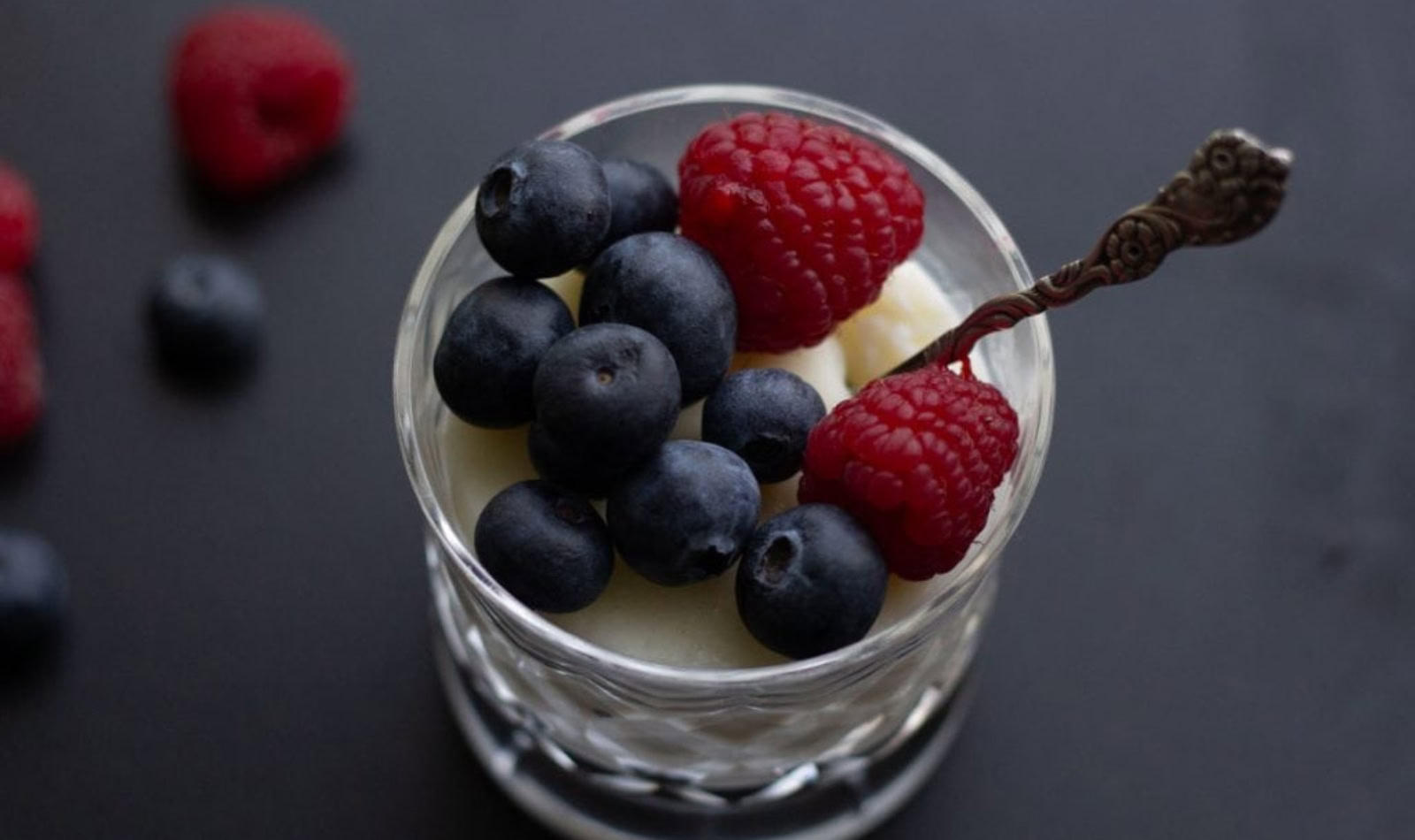 a glass of milk pudding with berries