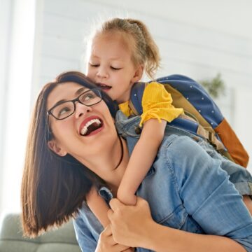 mom playing with little girl wearing backpack
