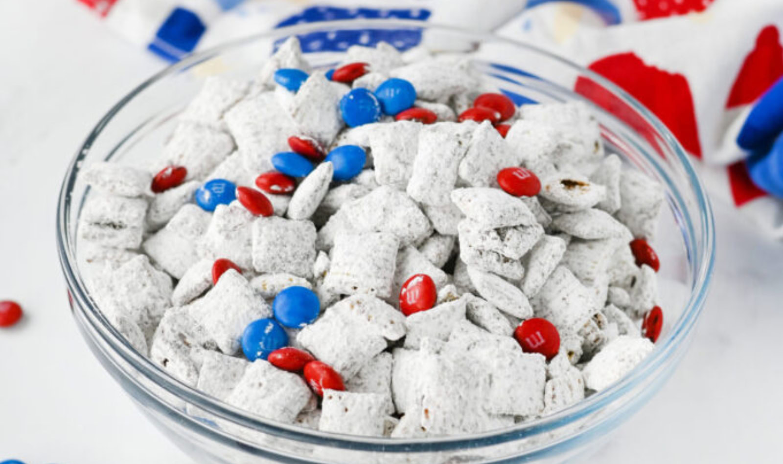 a bowl of puppy chow snack with red and blue m&ms