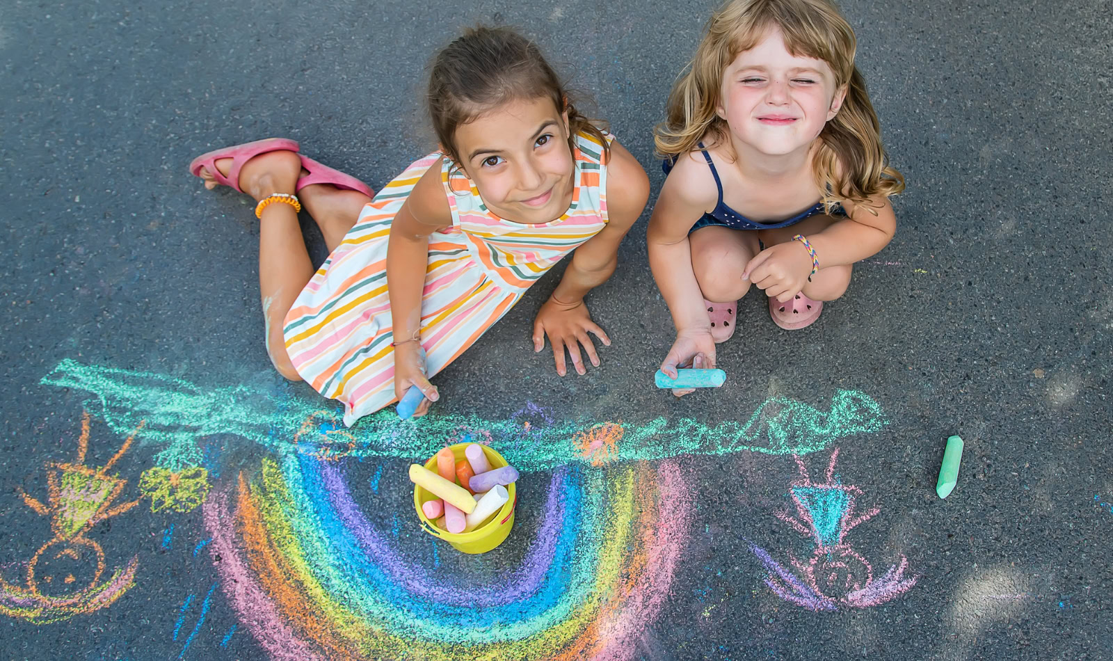 girls making chalk art on pavement