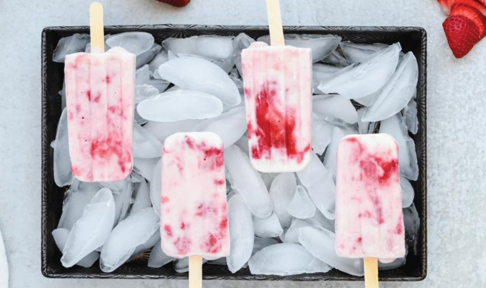 a panful of ice displaying strawberry yogurt popsicles