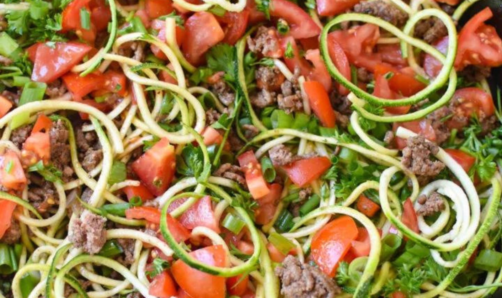 image tomatoes, zucchini and other spiralized veggies in a cast iron skillet