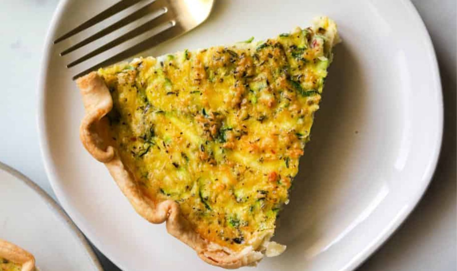 white plate with zucchini-and-bacon-quiche and a silver fork