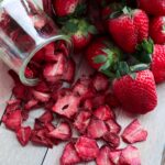 fresh strawberries next to a jar of dried strawberries