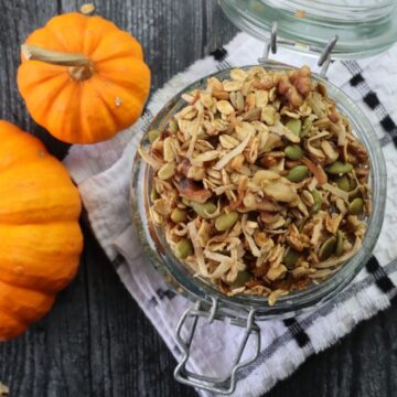 a jar of granola with mini pumpkins on a wooden table