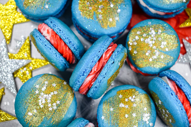 blue macarons with red frosting filling, and gold sprinkles