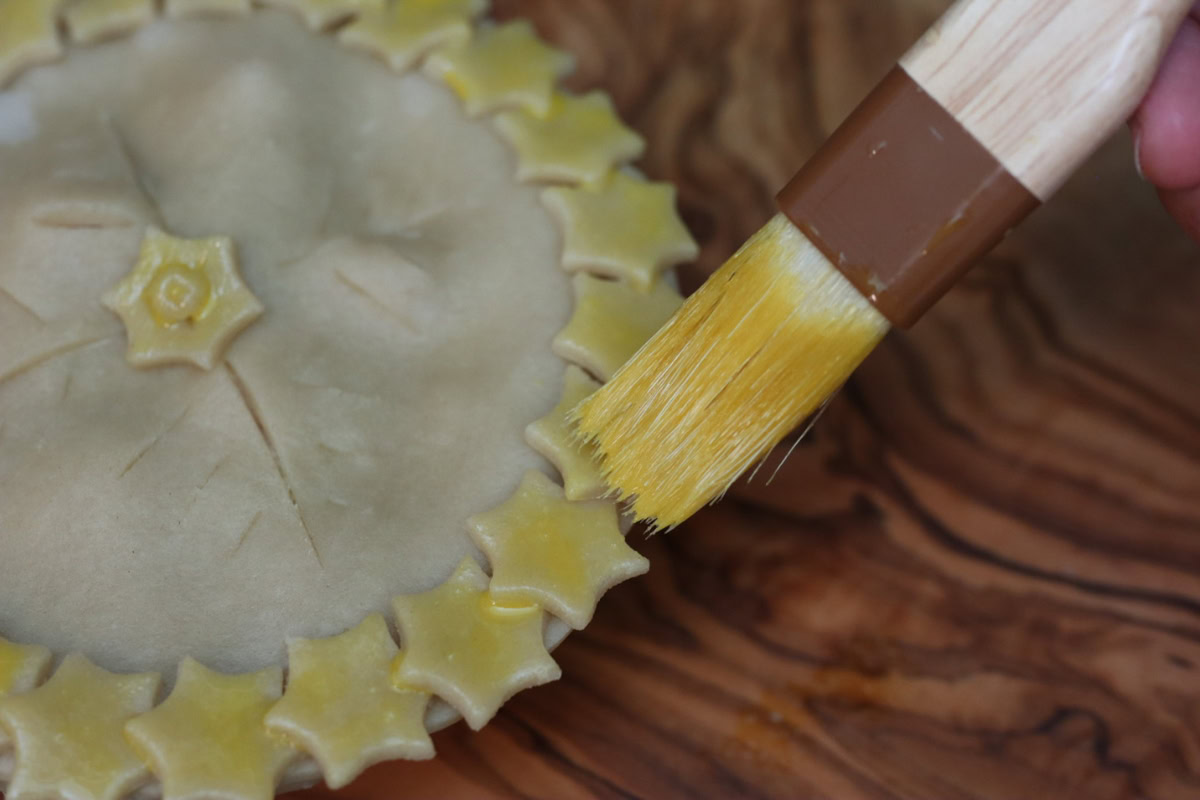 painting egg wash on pie crust